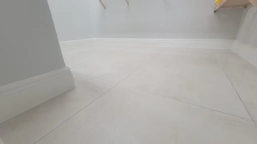 Large-format porcelain tile floor with new baseboard trim