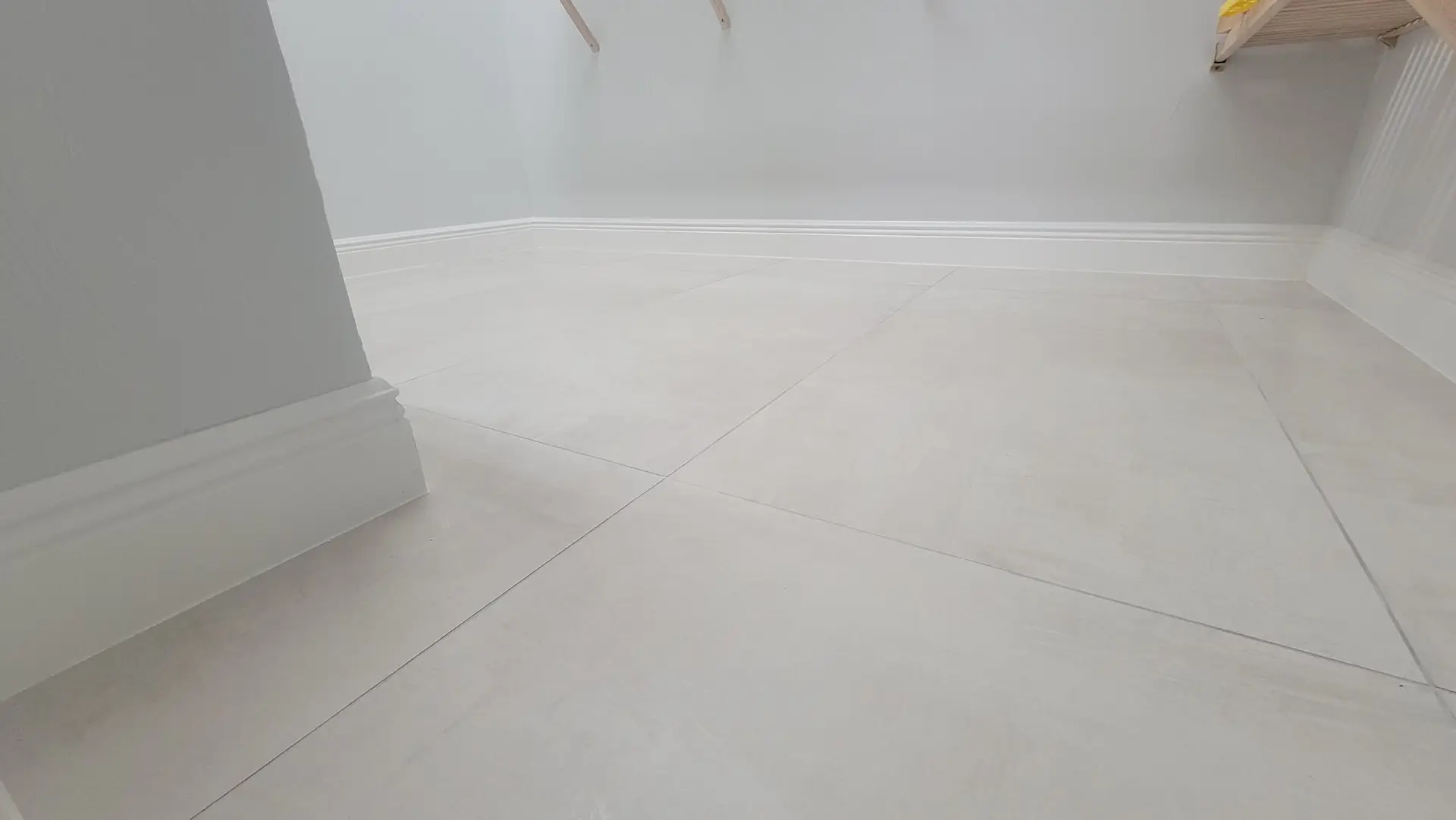 Large-format porcelain tile floor with new baseboard trim installed by Harpy Enterprises