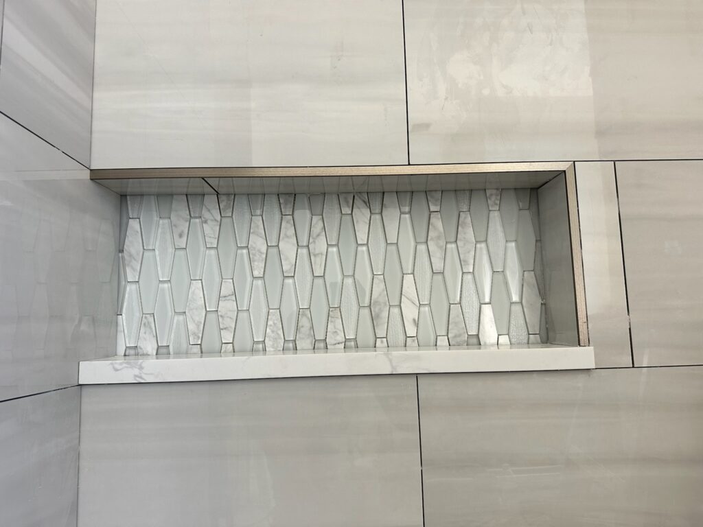 Shower niche with mosaic tile and metal edge trim before grouting