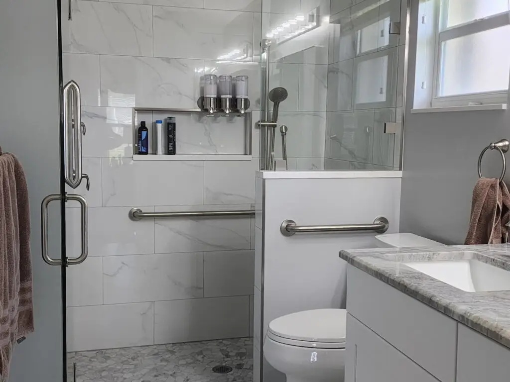 Walk-in shower with large-format wall tile, recessed niche, and mosaic shower floor