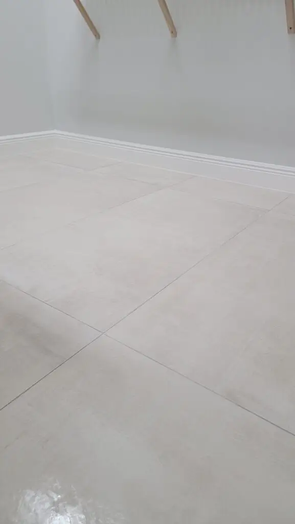 24×48 large-format porcelain tile flooring with white baseboards and painted walls at the Hernandez Residence in Naples, Florida.