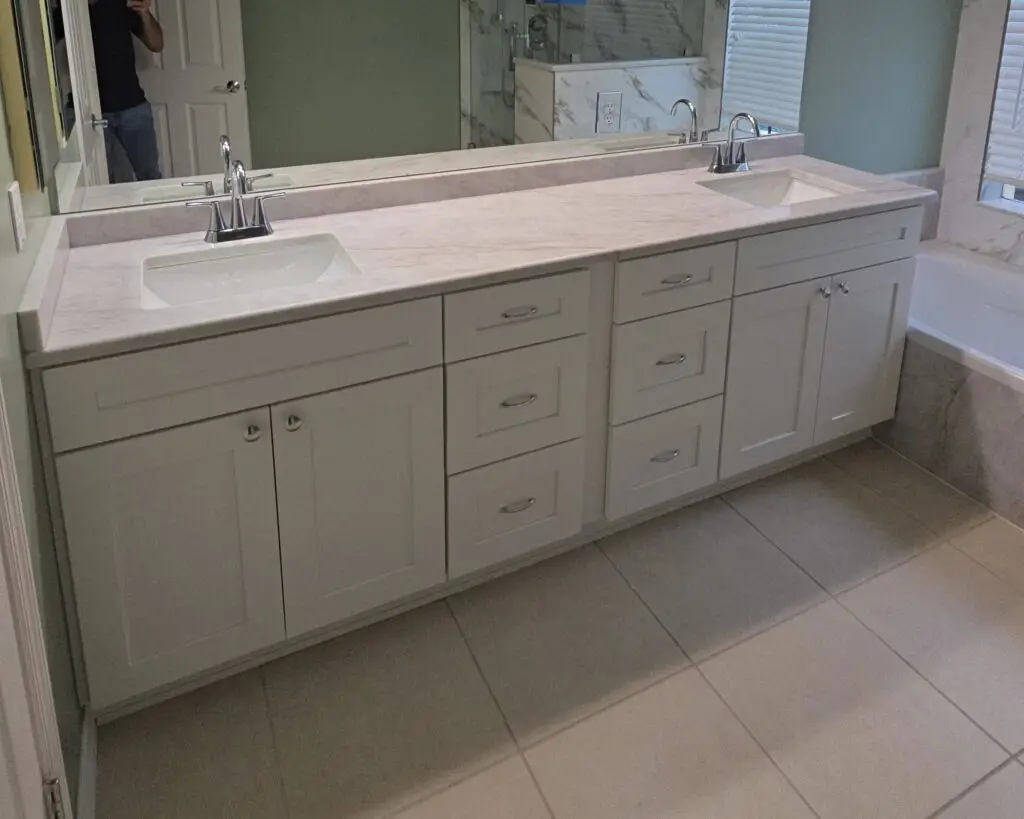 White shaker bathroom vanity with a Taj Mahal natural stone countertop in an Alva home