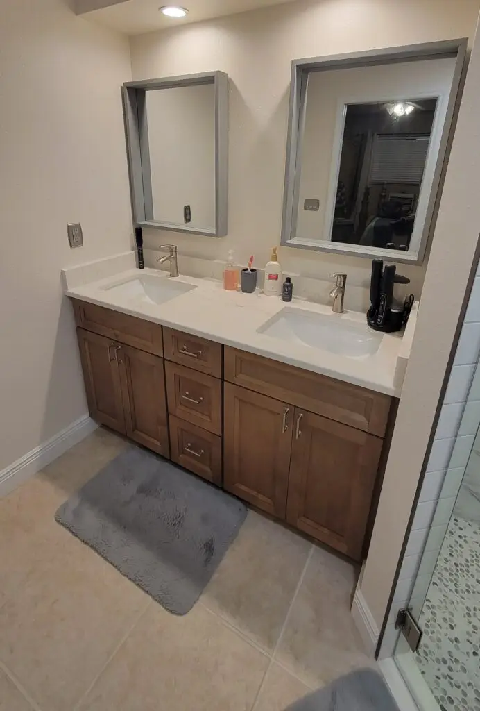 Completed bathroom with a wood-tone vanity, 3 cm quartz countertop, mirrors, and coordinated finishes in Cape Coral