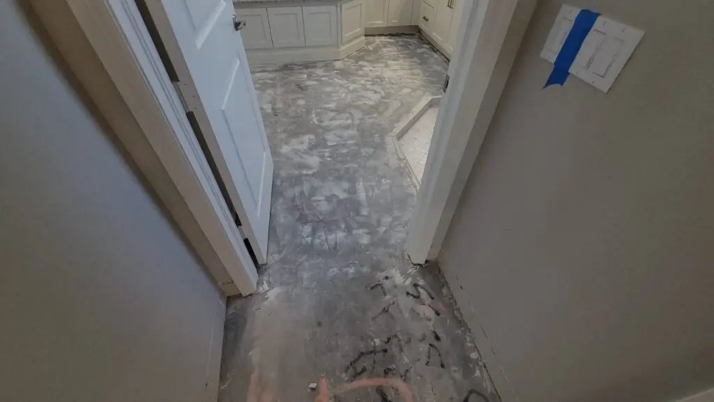 Bathroom concrete slab exposed and mechanically ground after removal of the existing floor tile in a Naples home